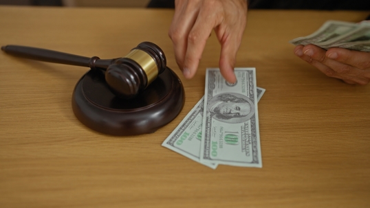 Man putting money down next to a gavel